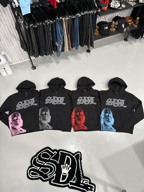 Stylish black hoodies featuring SDI logo and vibrant portrait prints in pink, gray, red, and blue. Perfect for street fashion.